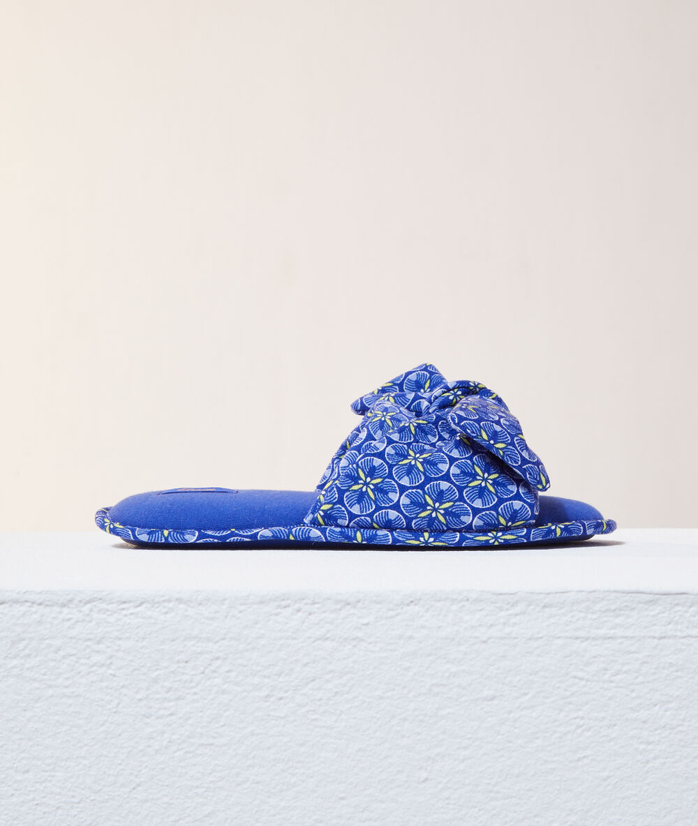 Zapatillas tipo chancla con lazo azul.