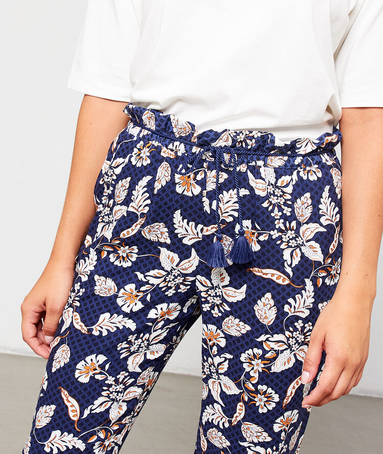 Pantalón estampado floral con pompones decorativos azul marino.